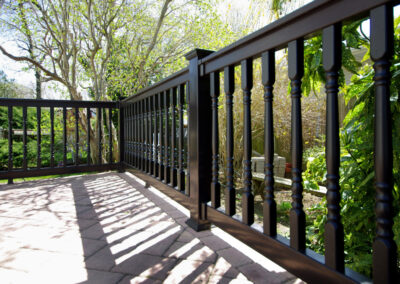 This black Grand Illusions 'T' top vinyl deck railing features Colonial balusters for an added touch of elegance.